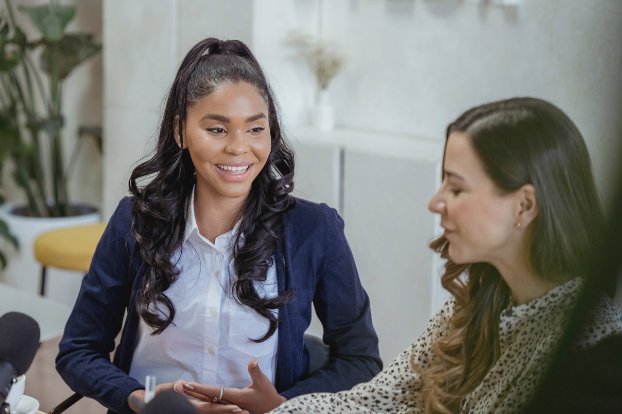 Two Business Women Sitting Down Smiling