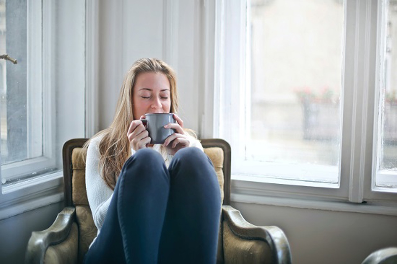 Woman Sitting In A Comfy Chair Holding Gray Ceramic Mug