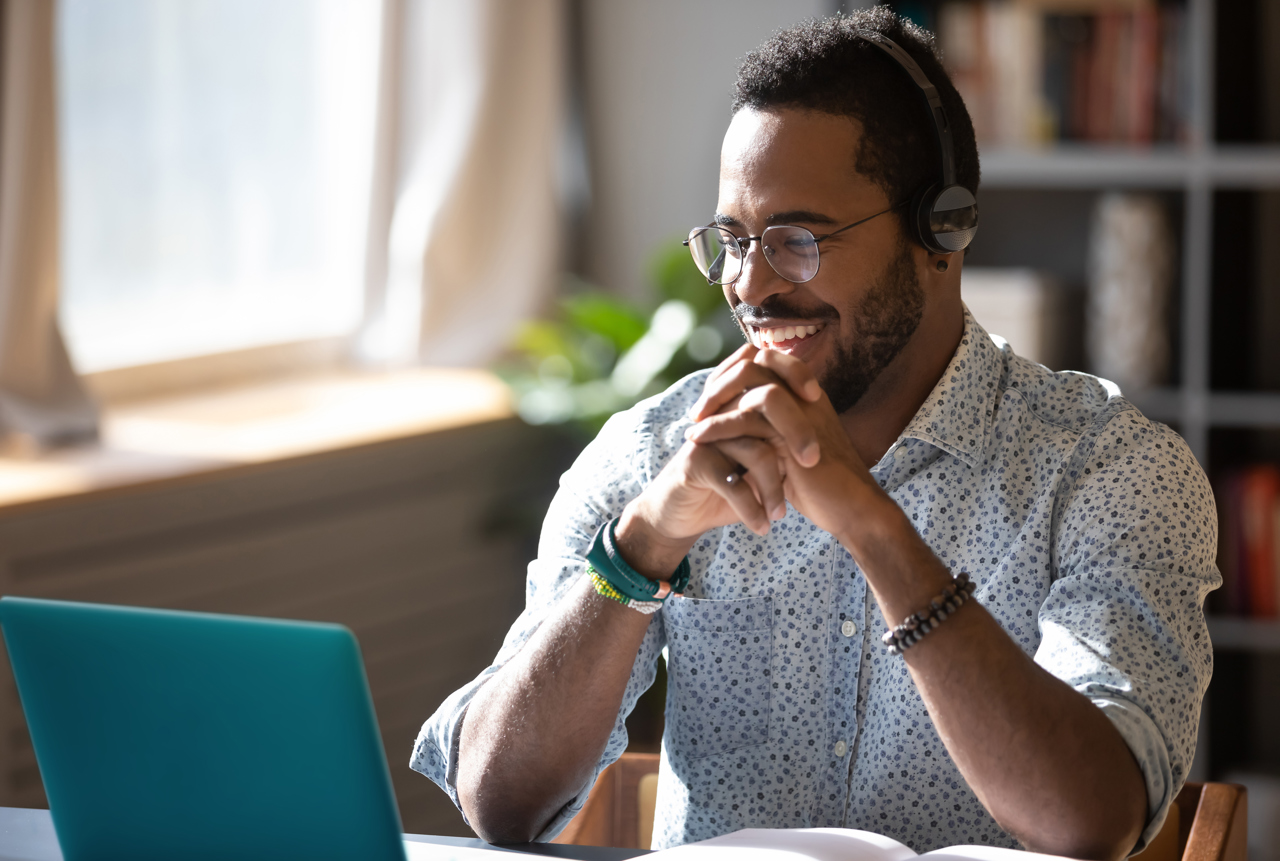 A man smiling working on a laptop